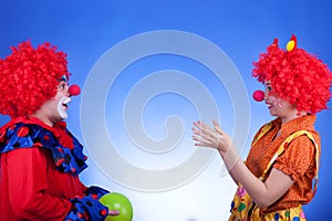 Clown couple playing with ballon on blue background