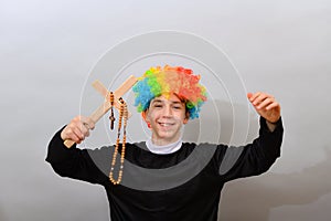 A clown dressed as a Catholic pastor with a cross and a rosary. The concept of blasphemy and ridicule of religion photo
