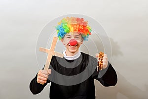 A clown dressed as a Catholic pastor with a cross and a rosary. The concept of blasphemy and ridicule of religion