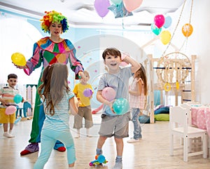 Clown entertains children at birthday party. Kids play with colorful ballons