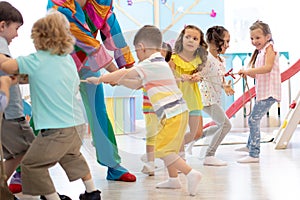 Clown entertains children at birthday party. Kids teams compete joyfully pulling rope