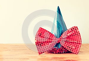 Clown hat and big bow tie over wooden table. filtered image.