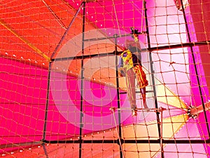 A clown on high flying trapeze under colurful tent