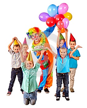 Clown holding cake on birthday with group children.