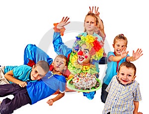 Clown holding cake on birthday with group children.