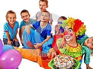 Clown holding cake on birthday with group children.