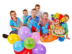 Clown holding cake on birthday with group children.