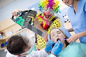 Clown from horror with chainsaw in dental clinic