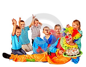 Clown keeps cake on birthday with group children.