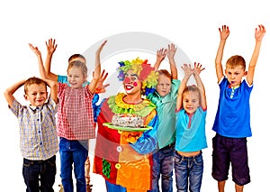 Clown keeps cake on birthday with group children.