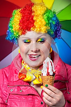 Clown with rainbow make up eating ice cream photo
