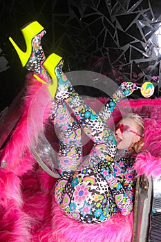 Club party blonde girl in acid anime style spandex catsuit with mirror car with pink fur ready for crazy clubbing life