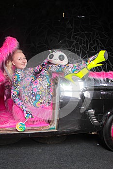 Club party blonde girl in acid anime style spandex catsuit with mirror car with pink fur ready for crazy clubbing life