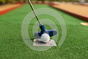 A club prepares to hit a ball during a mini golf game