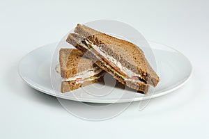 Club sandwich with chicken and tomatoes on rye bread in white plate isolated. club sandwich