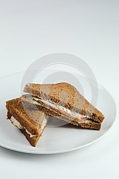 Club sandwich with chicken and tomatoes on rye bread in white plate isolated. club sandwich