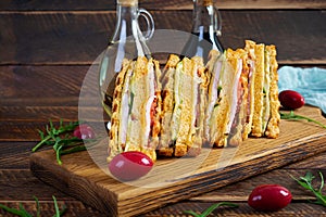 Club sandwich with ham, cheese, tomato and salad. Grilled sandwich with dried tomatoes bread