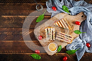 Club sandwich with ham, tomato, cheese and spinach. Grilled panini. Top view photo