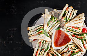 Club sandwich with ham, tomato, cucumber, cheese, and arugula