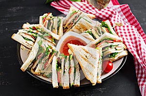 Club sandwich with ham, tomato, cucumber, cheese, and arugula