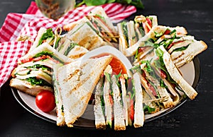 Club sandwich with ham, tomato, cucumber, cheese, and arugula