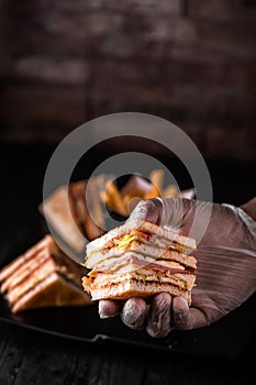 Club Sandwich in hand isolated on wooden table side view of arabic food