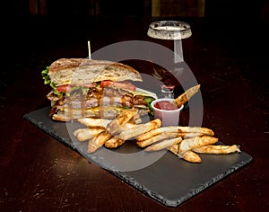Club sandwich with juices oozing out with fries and a beer