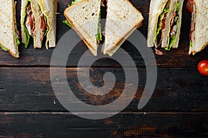 Club sandwich with meat, cheese, tomato, ham, on dark wooden background, top view with copy space for text