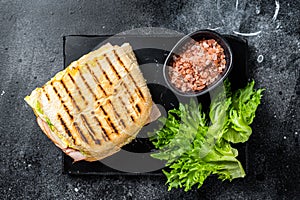 Club sandwich panini with ham, tomato, cheese and basil. Black background. top view