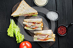 Club sandwich panini with ham, tomato, cheese, on black wooden table, top view