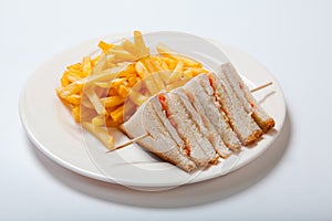 Club sandwiches with chicken and french fries on a white plate