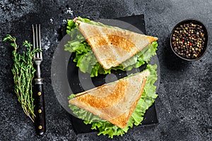 Club sandwiches with pork ham, cheese, tomatoes and lettuce on a wooden cutting board. Black background. Top view