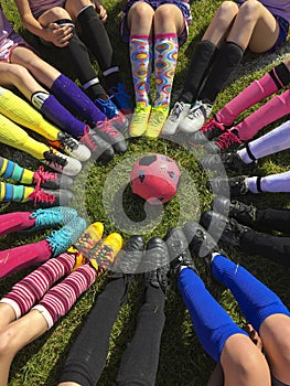 Club soccer team sitting around a soccer ball