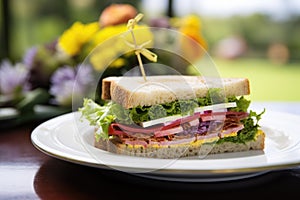 a clubhouse sandwich with a missing bite placed near a flowering plant