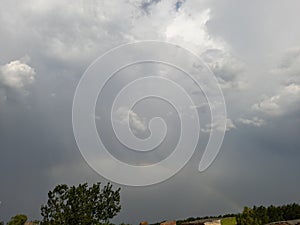 Cludy sky and trees with rainbow