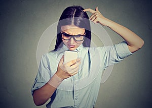 Clueless looking girl having troubles with smartphone. Complicated technology concept