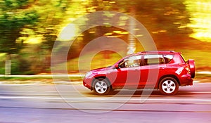 Fast driving red car on the road at sunset