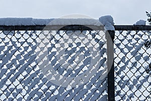 Clumps of fluffy white snow collected in a fence