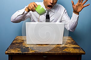 Clumsy businessman spilling coffee on his laptop computer