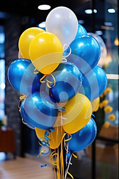 Cluster of blue and yellow balloons with white ribbons in indoor setting