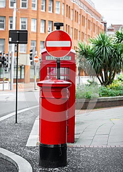 Cluster of bright royal red traditional old telephone box letter post box and no entry sign on beautiful summer day and no people.