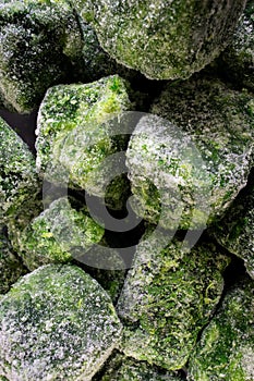 A cluster of frozen spinach leaves, covered in a thin layer of frost, lies neatly stacked.