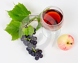 The cluster of grapes and apple lie near a wine glass with brand