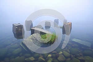 cluster of sunken stone sarcophagi in a misty lake