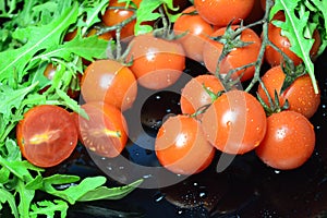 Cherry tomatoes and arugula on a black plate