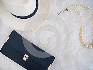 Clutch bag Hat and Pearl necklace on white fur Background