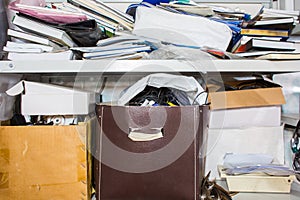 Clutter concept - lots of books, papers, boxes on shelf photo