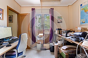 Cluttered home office and workshop with tools, desk, and computer setup