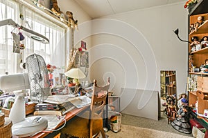 a cluttered room with a desk and a window