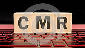 CMR Contract Management Review or Clear Motion Rate written on wooden cubes on the laptop keyboard